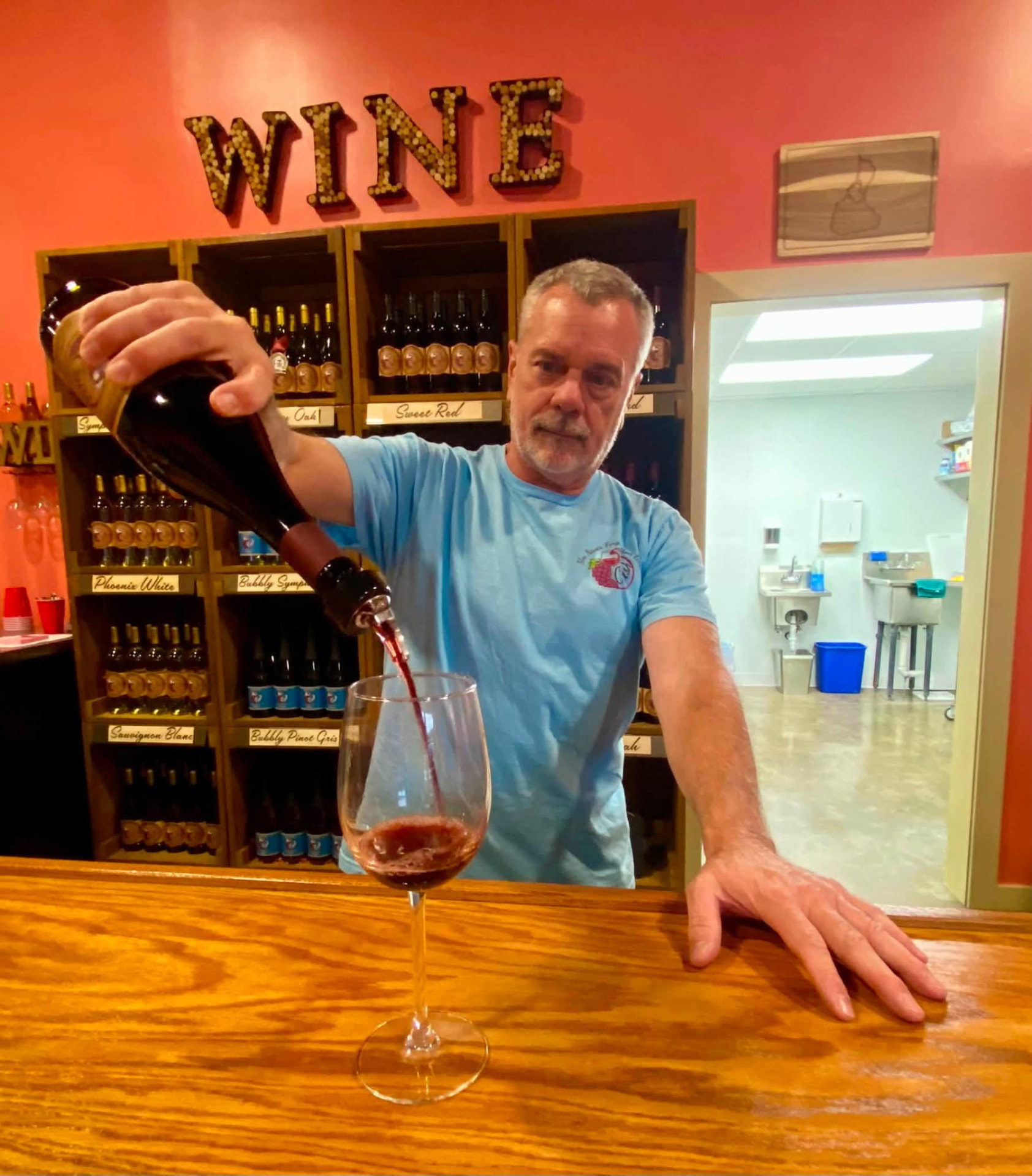 Arnie Schloemann pouring a glass of red wine behind the bar